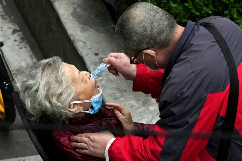 Seseorang dengan pakaian pelindung meemanjat barikade yang dipasang di sekitar area tertutup, selama penguncian untuk mengekang penyebaran penyakit coronavirus (COVID-19) di Shanghai, China, Senin (11/4/2022). (REUTERS/Aly Song)