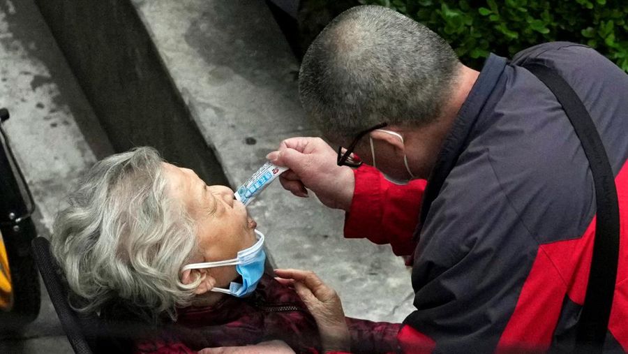 Seseorang dengan pakaian pelindung meemanjat barikade yang dipasang di sekitar area tertutup, selama penguncian untuk mengekang penyebaran penyakit coronavirus (COVID-19) di Shanghai, China, Senin (11/4/2022). (REUTERS/Aly Song)