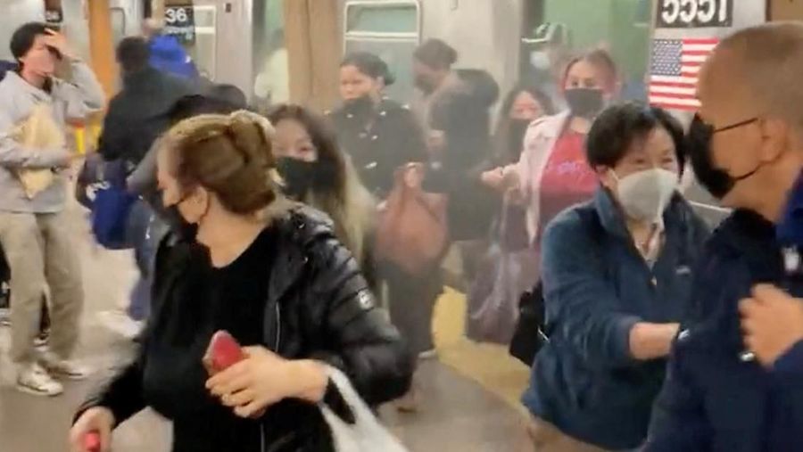 Penumpang membantu korban penembakan di luar gerbong kereta bawah tanah di wilayah Brooklyn di New York, Selasa (12/4/2022).  Sejumlah penumpang diberondong tembakan pria tak dikenal di kereta bawah tanah di New York City saat jam sibuk pagi hari yang menyebabkan penumpang terluka berdarah di peron kereta. (Will B Wylde via AP)