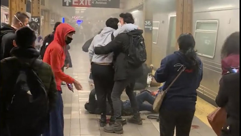 Penumpang membantu korban penembakan di luar gerbong kereta bawah tanah di wilayah Brooklyn di New York, Selasa (12/4/2022).  Sejumlah penumpang diberondong tembakan pria tak dikenal di kereta bawah tanah di New York City saat jam sibuk pagi hari yang menyebabkan penumpang terluka berdarah di peron kereta. (Will B Wylde via AP)