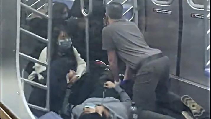 Seorang penumpang membantu korban penembakan di dalam gerbong kereta bawah tanah di wilayah Brooklyn di New York, Selasa (12/4/2022). Sejumlah penumpang diberondong tembakan pria tak dikenal di kereta bawah tanah di New York City saat jam sibuk pagi hari yang menyebabkan penumpang terluka berdarah di peron kereta. (Will B Wylde via AP)