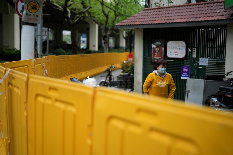 Kondisi Jalan Kosong di Shanghai China Saat Lockdown Seorang warga terlihat di balik pembatas yang menutup area yang dikunci di tengah pandemi penyakit virus corona (COVID-19), di Shanghai, China, Kamis (14/4/2022). (REUTERS/Aly Song)