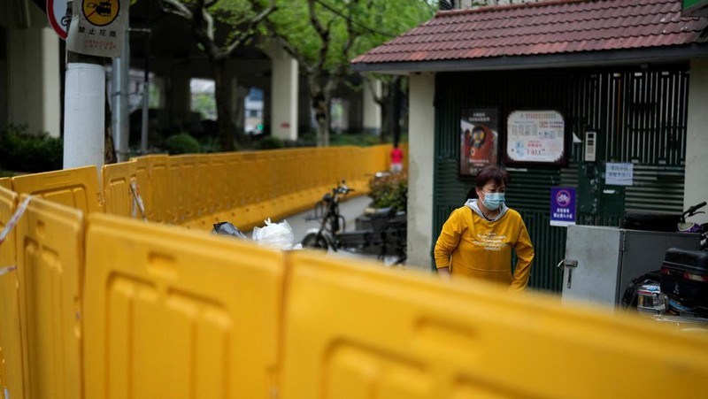 Seorang warga terlihat di balik pembatas yang menutup area yang dikunci di tengah pandemi penyakit virus corona (COVID-19), di Shanghai, China, Kamis (14/4/2022). (REUTERS/Aly Song)