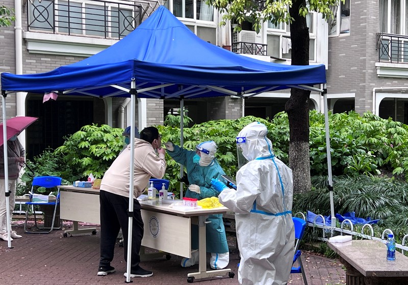 Seorang warga terlihat di balik pembatas yang menutup area yang dikunci di tengah pandemi penyakit virus corona (COVID-19), di Shanghai, China, Kamis (14/4/2022). (REUTERS/Aly Song)