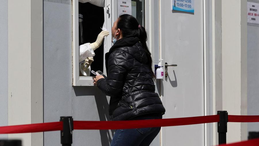 Seorang warga terlihat di balik pembatas yang menutup area yang dikunci di tengah pandemi penyakit virus corona (COVID-19), di Shanghai, China, Kamis (14/4/2022). (REUTERS/Aly Song)