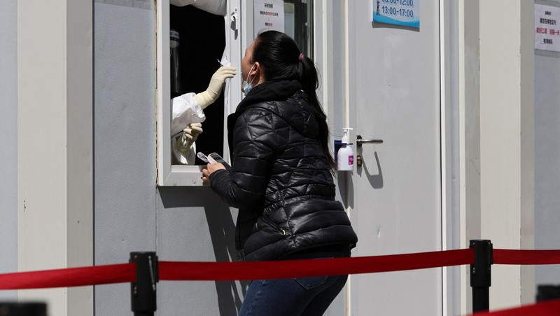 Seorang warga terlihat di balik pembatas yang menutup area yang dikunci di tengah pandemi penyakit virus corona (COVID-19), di Shanghai, China, Kamis (14/4/2022). (REUTERS/Aly Song)