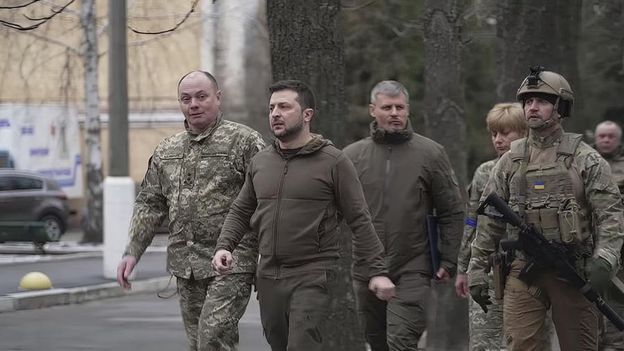 Presiden Ukraina Volodymyr Zelensky berjalan ke rumah sakit untuk mengunjungi dokter, perawat, dan anggota militer yang terluka di Kyiv, Ukraina, Minggu (13/3/2022).  (Ukrainian Presidential Press Office via AP)