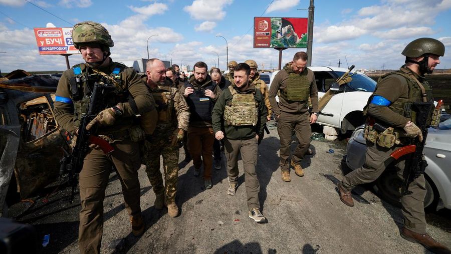 Presiden Ukraina Volodymyr Zelensky berjalan melewati mobil-mobil yang hancur di kota Irpin, saat serangan Rusia di Ukraina berlanjut, di luar Kyiv, Ukraina,  Senin (4/4/2022).  (Ukrainian Presidential Press Service/Handout via REUTERS)