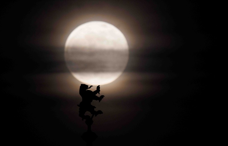 APTOPIX Germany Daily Life The moon rises behind the Alpina Bahn at Frankfurt's Dippemess, a traditional German fair, Saturday, April 16, 2022. (Sebastian Gollnow/dpa via AP)