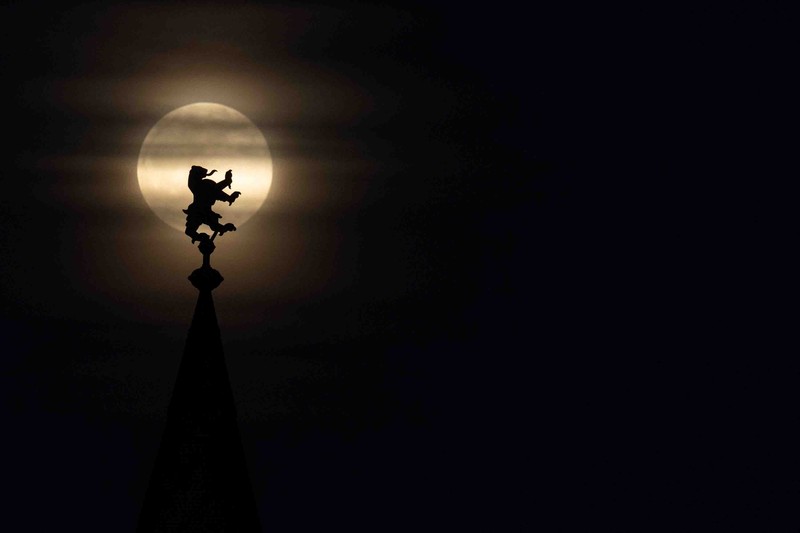 APTOPIX Germany Daily Life The moon rises behind the Alpina Bahn at Frankfurt's Dippemess, a traditional German fair, Saturday, April 16, 2022. (Sebastian Gollnow/dpa via AP)