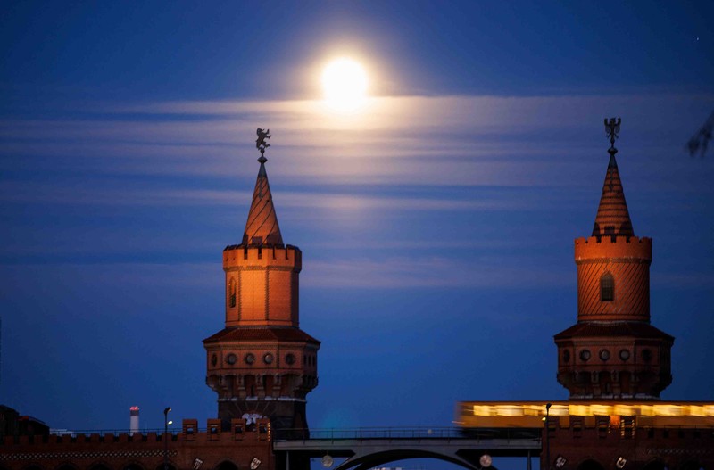 The moon rises behind the Alpina Bahn at Frankfurt's Dippemess, a traditional German fair, Saturday, April 16, 2022. (Sebastian Gollnow/dpa via AP)