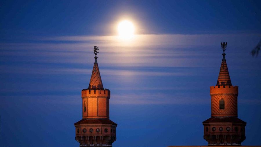 The moon rises behind the Alpina Bahn at Frankfurt's Dippemess, a traditional German fair, Saturday, April 16, 2022. (Sebastian Gollnow/dpa via AP)