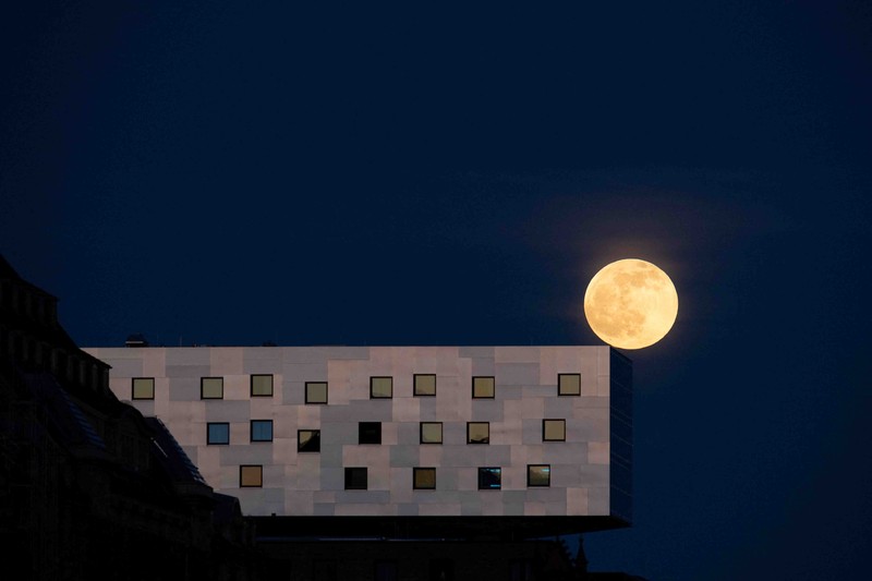 APTOPIX Germany Daily Life The moon rises behind the Alpina Bahn at Frankfurt's Dippemess, a traditional German fair, Saturday, April 16, 2022. (Sebastian Gollnow/dpa via AP)