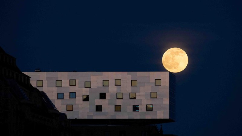 The moon rises behind the Alpina Bahn at Frankfurt's Dippemess, a traditional German fair, Saturday, April 16, 2022. (Sebastian Gollnow/dpa via AP)