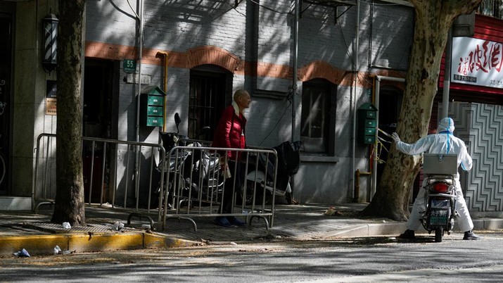 HEALTH-CORONAVIRUS/CHINA A worker in protective suit talks with a resident at a residential area under lockdown amid the coronavirus disease (COVID-19) pandemic, in Shanghai, China April 17, 2022. REUTERS/Aly Song