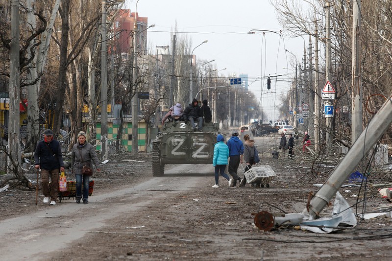 Service members of pro-Russian troops and civilians sit atop of an armoured vehicle during Ukraine-Russia conflict in the southern port city of Mariupol, Ukraine April 17, 2022. REUTERS/Alexander Ermochenko