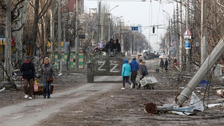 Service members of pro-Russian troops and civilians sit atop of an armoured vehicle during Ukraine-Russia conflict in the southern port city of Mariupol, Ukraine April 17, 2022. REUTERS/Alexander Ermochenko