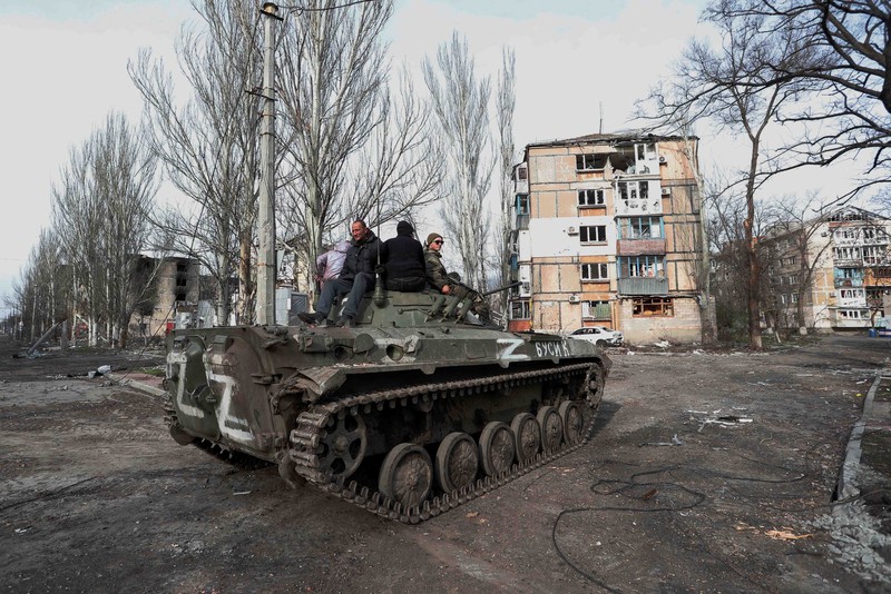 Service members of pro-Russian troops and civilians sit atop of an armoured vehicle during Ukraine-Russia conflict in the southern port city of Mariupol, Ukraine April 17, 2022. REUTERS/Alexander Ermochenko