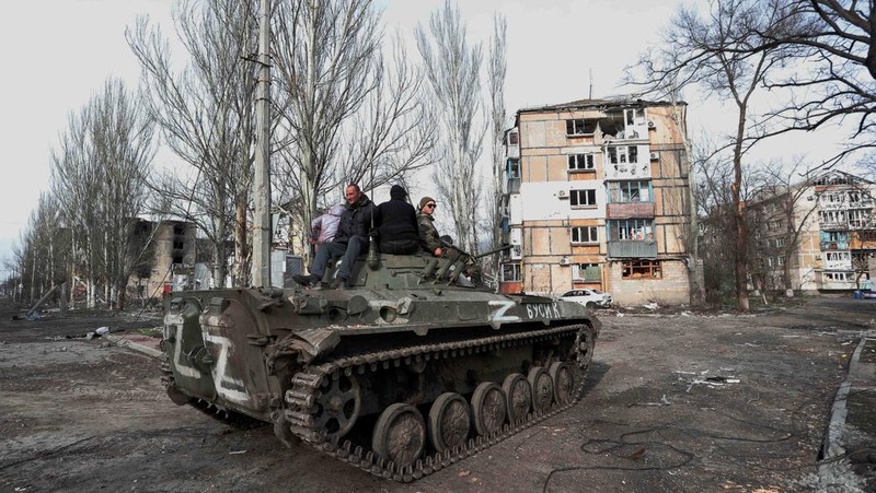 Service members of pro-Russian troops and civilians sit atop of an armoured vehicle during Ukraine-Russia conflict in the southern port city of Mariupol, Ukraine April 17, 2022. REUTERS/Alexander Ermochenko