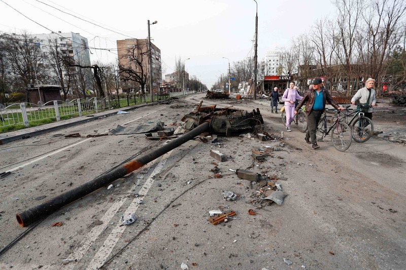 Service members of pro-Russian troops and civilians sit atop of an armoured vehicle during Ukraine-Russia conflict in the southern port city of Mariupol, Ukraine April 17, 2022. REUTERS/Alexander Ermochenko