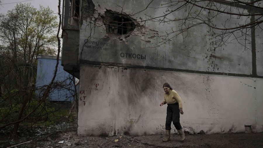 A woman walks next to a damaged building after a Russian bombardment in Kharkiv, Ukraine, Tuesday, April 19, 2022. Russia ratcheted up its battle for control of Ukraine’s eastern industrial heartland on Tuesday, intensifying assaults on cities and towns along a front hundreds of miles long in what officials on both sides described as a new phase of the war. (AP Photo/Felipe Dana)