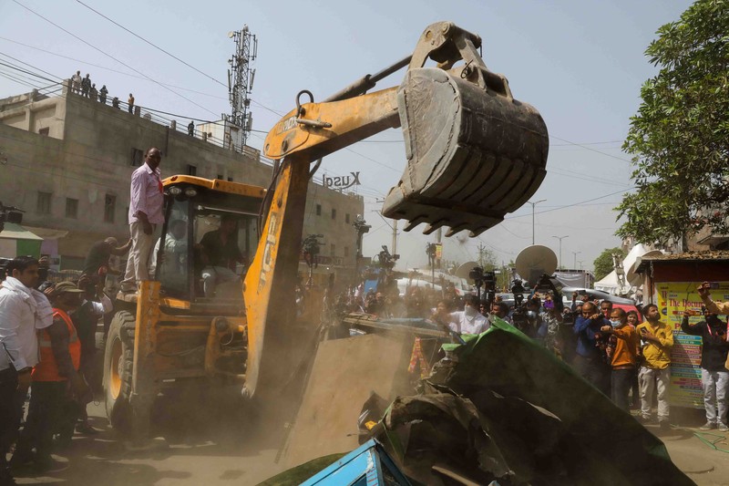 People watch the demolition of small illegal retail shops in a communally sensitive area in Jahangirpuri, in New Delhi, India, April 20, 2022. REUTERS/ Anushree Fadnavis