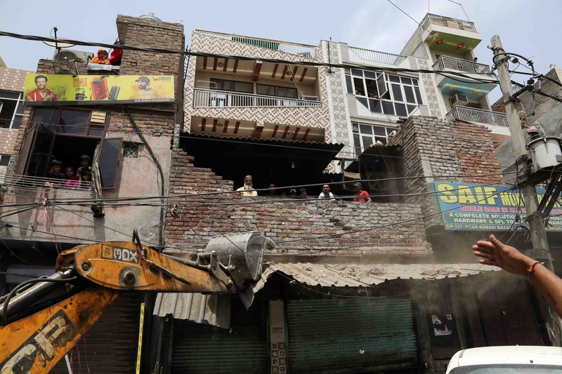 INDIA-POLITICS/UNREST People watch the demolition of small illegal retail shops in a communally sensitive area in Jahangirpuri, in New Delhi, India, April 20, 2022. REUTERS/ Anushree Fadnavis