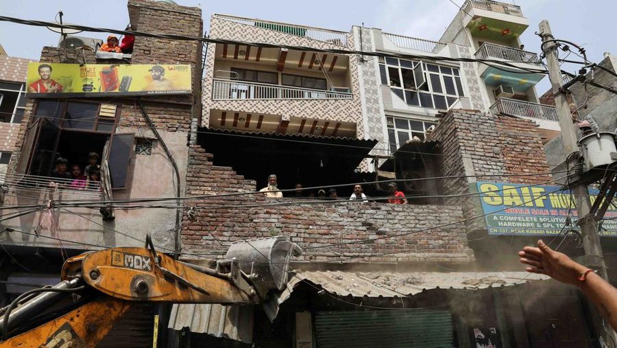 People watch the demolition of small illegal retail shops in a communally sensitive area in Jahangirpuri, in New Delhi, India, April 20, 2022. REUTERS/ Anushree Fadnavis