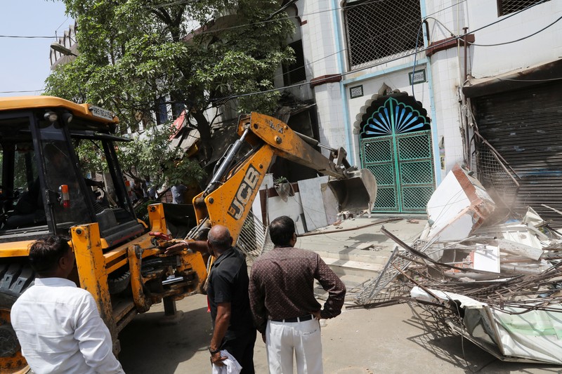 People watch the demolition of small illegal retail shops in a communally sensitive area in Jahangirpuri, in New Delhi, India, April 20, 2022. REUTERS/ Anushree Fadnavis