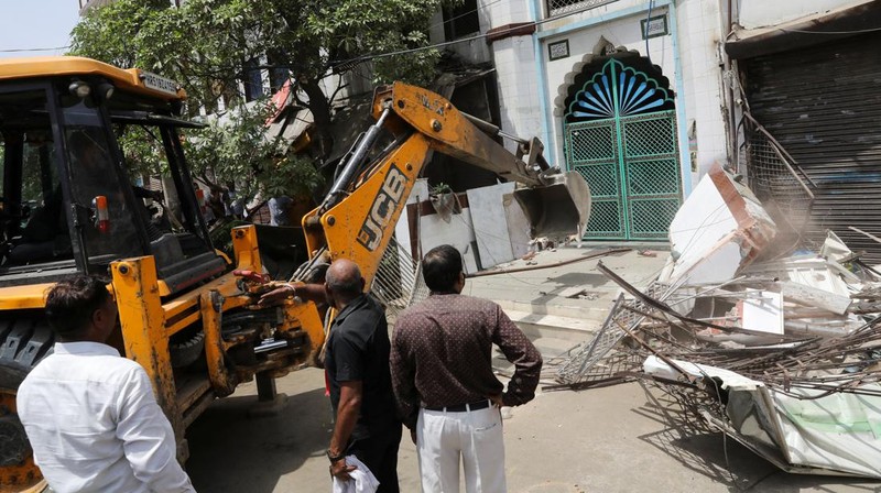 People watch the demolition of small illegal retail shops in a communally sensitive area in Jahangirpuri, in New Delhi, India, April 20, 2022. REUTERS/ Anushree Fadnavis