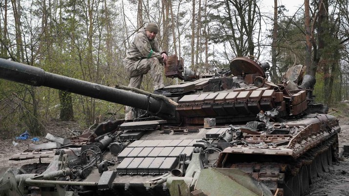 A Ukrainian soldier inspects a Russian tank after recent battles at the village of Moshchun close to Kyiv, Ukraine, Tuesday, April 19, 2022. (AP Photo/Efrem Lukatsky)