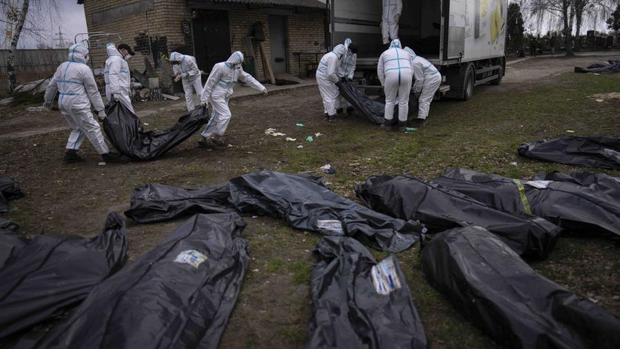 Volunteers load bodies of civilians killed in Bucha onto a truck to be taken to a morgue for investigation, in the outskirts of Kyiv, Ukraine, Tuesday, April 12, 2022. (AP Photo/Rodrigo Abd)
