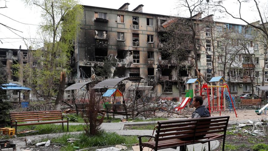 A man sits on a bench in front of a residential building heavily damaged during Ukraine-Russia conflict in the southern port city of Mariupol, Ukraine April 21, 2022. REUTERS/Alexander Ermochenko