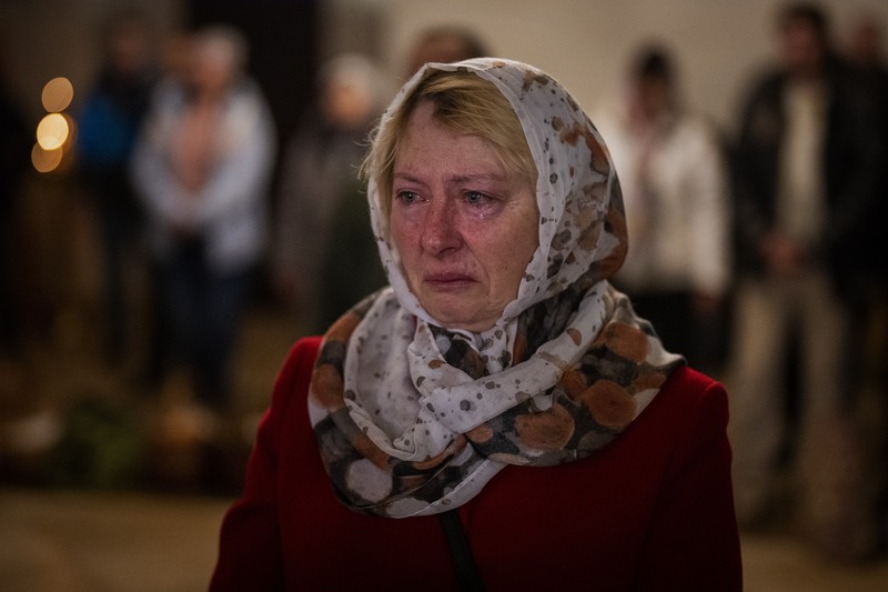 Seorang pastor Ukraina memberkati umat beriman saat mereka mengumpulkan kue tradisional dan telur yang dicat yang disiapkan untuk perayaan Paskah di Lviv, Ukraina, Sabtu (23/2/2022). (AP Photo/Mykola Tys)