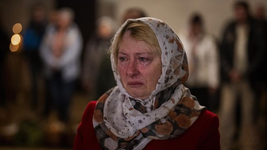 Seorang pastor Ukraina memberkati umat beriman saat mereka mengumpulkan kue tradisional dan telur yang dicat yang disiapkan untuk perayaan Paskah di Lviv, Ukraina, Sabtu (23/2/2022). (AP Photo/Mykola Tys)