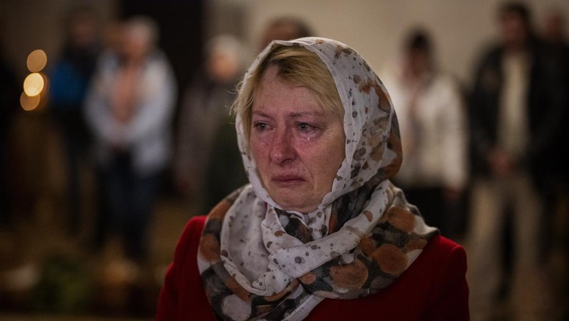 Seorang pastor Ukraina memberkati umat beriman saat mereka mengumpulkan kue tradisional dan telur yang dicat yang disiapkan untuk perayaan Paskah di Lviv, Ukraina, Sabtu (23/2/2022). (AP Photo/Mykola Tys)
