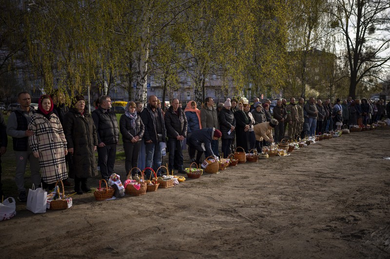 Seorang pastor Ukraina memberkati umat beriman saat mereka mengumpulkan kue tradisional dan telur yang dicat yang disiapkan untuk perayaan Paskah di Lviv, Ukraina, Sabtu (23/2/2022). (AP Photo/Mykola Tys)