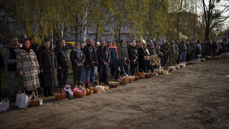 Seorang pastor Ukraina memberkati umat beriman saat mereka mengumpulkan kue tradisional dan telur yang dicat yang disiapkan untuk perayaan Paskah di Lviv, Ukraina, Sabtu (23/2/2022). (AP Photo/Mykola Tys)