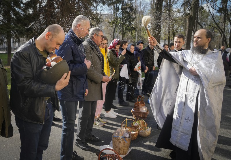 Seorang pastor Ukraina memberkati umat beriman saat mereka mengumpulkan kue tradisional dan telur yang dicat yang disiapkan untuk perayaan Paskah di Lviv, Ukraina, Sabtu (23/2/2022). (AP Photo/Mykola Tys)