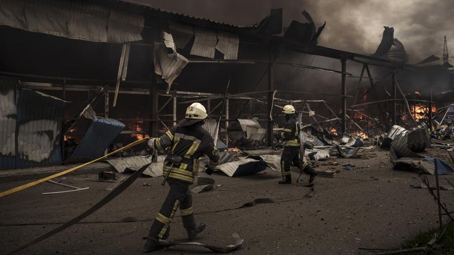 Petugas pemadam kebakaran bekerja memadamkan api akibat bom Rusia di gudang di Kharkiv, Ukraina, Sabtu (23/4/2022). (AP Photo/Felipe Dana)