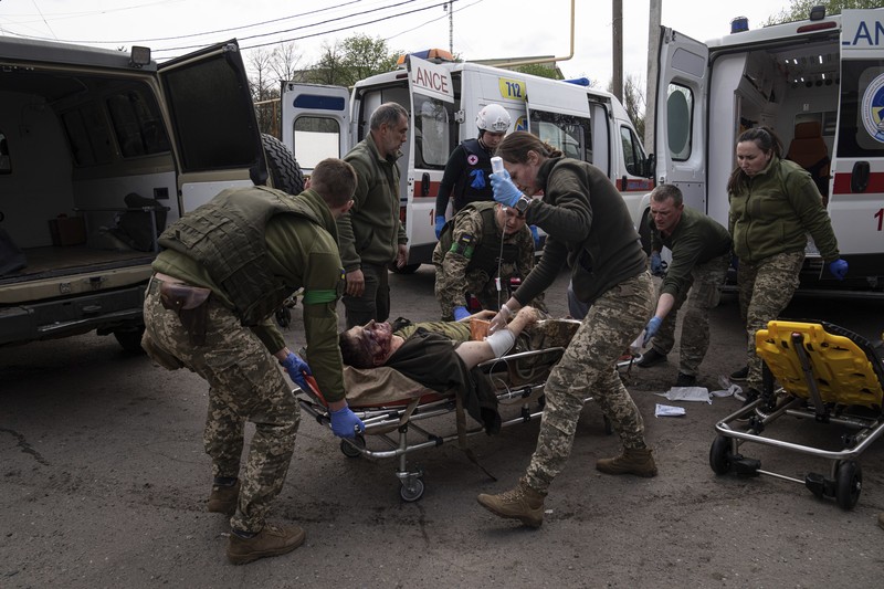 Petugas medis militer Ukraina memindahkan seorang prajurit Ukraina yang terluka ke sebuah rumah sakit di wilayah Donetsk, Ukraina timur, Sabtu (23/4/2022). (AP Photo/Evgeniy Maloletka)