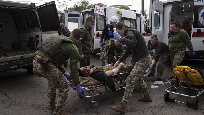 Petugas medis militer Ukraina memindahkan seorang prajurit Ukraina yang terluka ke sebuah rumah sakit di wilayah Donetsk, Ukraina timur, Sabtu (23/4/2022). (AP Photo/Evgeniy Maloletka)