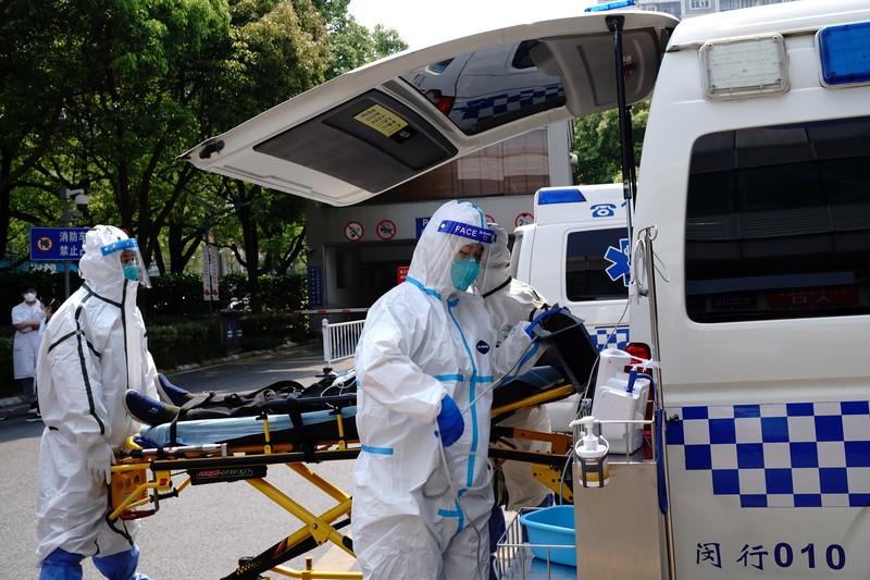 Petugas medis memindahkan seorang pasien dari ambulans di Rumah Sakit Minhang yang berafiliasi dengan Universitas Fudan di Shanghai. (AP/Zhang Jiansong)