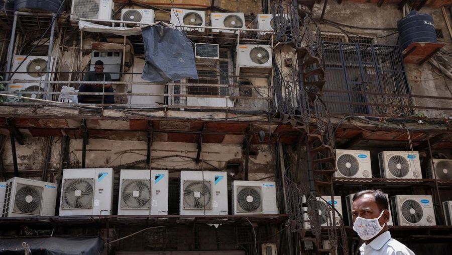 SOUTHASIA-WEATHER/HEATWAVE A man uses his mobile phone as he sits amidst the outer units of air conditioners, at the rear of a commercial building in New Delhi, India, April 30, 2022. REUTERS/Adnan Abidi