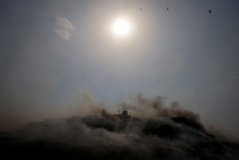 SOUTHASIA-WEATHER/HEATWAVE An excavator tries to contain the fire as smoke billows from burning garbage on a hot summer day, at the Bhalswa landfill site in New Delhi, India, April 29, 2022. REUTERS/Adnan Abidi TPX IMAGES OF THE DAY