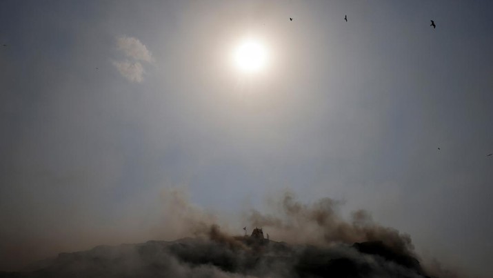 SOUTHASIA-WEATHER/HEATWAVE An excavator tries to contain the fire as smoke billows from burning garbage on a hot summer day, at the Bhalswa landfill site in New Delhi, India, April 29, 2022. REUTERS/Adnan Abidi TPX IMAGES OF THE DAY