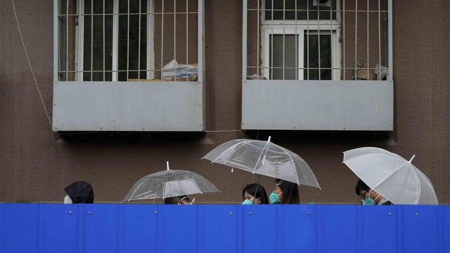 A resident wearing a face mask stands watch behind a barricaded fence of a locked-down residential complex on Thursday, April 28, 2022, in Beijing. China employs a variety of metal barricades, metal sheeting and door locks to keep people inside their apartments, buildings or complexes during lockdowns. The barriers have been deployed in multiple cities across China as part of the fight against COVID-19. (AP Photo/Andy Wong)