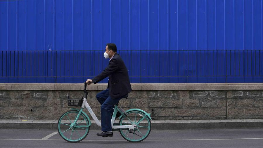 A resident wearing a face mask stands watch behind a barricaded fence of a locked-down residential complex on Thursday, April 28, 2022, in Beijing. China employs a variety of metal barricades, metal sheeting and door locks to keep people inside their apartments, buildings or complexes during lockdowns. The barriers have been deployed in multiple cities across China as part of the fight against COVID-19. (AP Photo/Andy Wong)