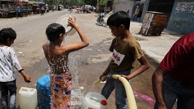 Suhu Musim Panas India Seorang anak laki-laki mandi saat ia menunggu untuk mengambil air dari sebuah truk tangki saat musim panas di New Delhi, India, Minggu (1/5/2022). (REUTERS/Anushree Fadnavis)