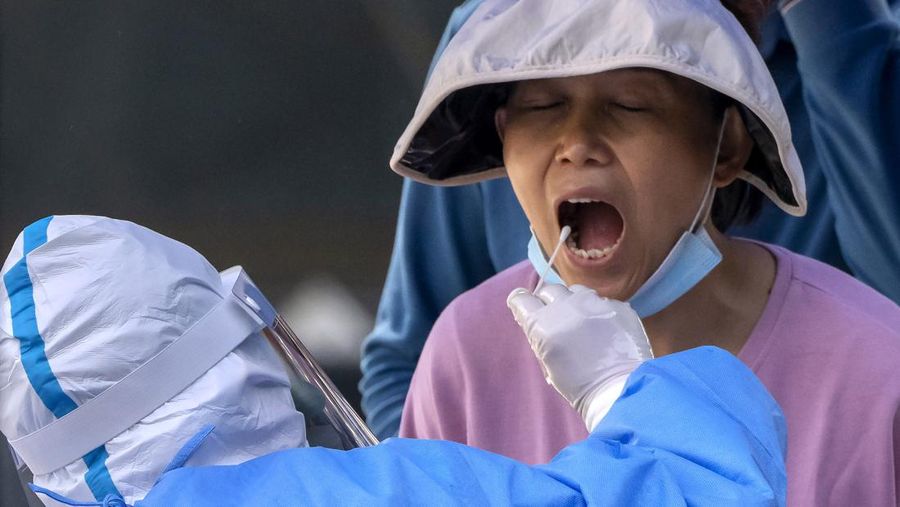 Seorang pekerja yang mengenakan pakaian pelindung melakukan tes COVID-19 massal di Beijing, Kamis (5/4/2022). (AP Photo/Mark Schiefelbein)